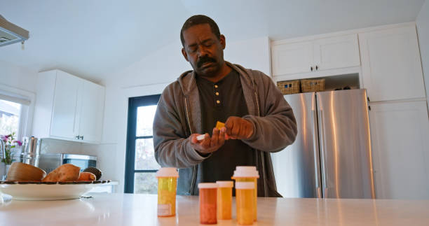 hombre afroamericano toma píldora de frasco de medicina - opening bottle pill bottle pill fotografías e imágenes de stock