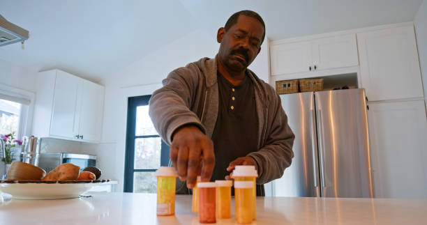 istock African American Man Looking at His Pill Bottles on The Kitchen Counter 1476004315