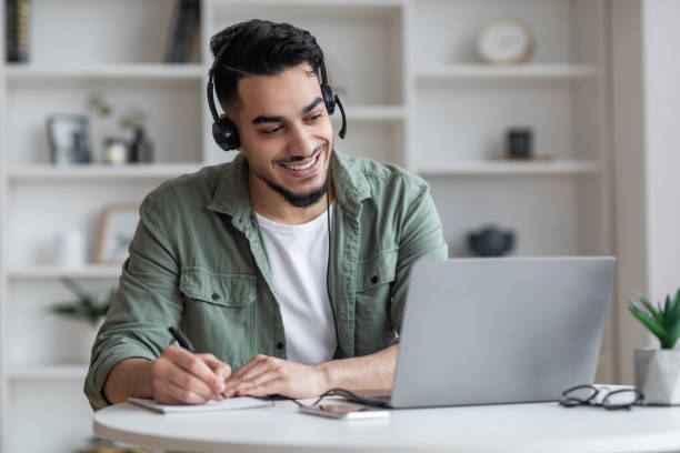 istock Distance Learning. Arab Man In Headset Study Online With Laptop At Home 1476004367
