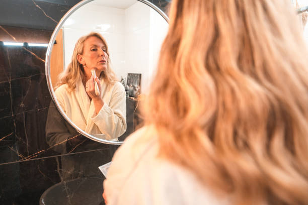 istock Mature Female In A Modern Bathroom Doing Her Makeup 1476011683