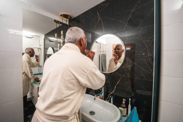 istock Hispanic Mature Male Brushing His Teeth In A Bathrobe 1476011746