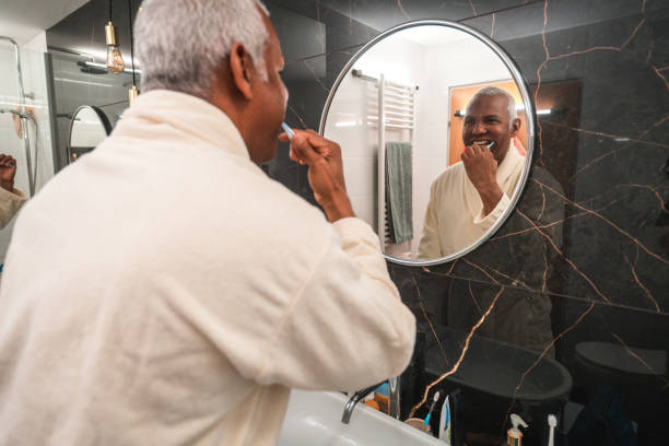 istock Hispanic Mature Male Brushing His Teeth In A Bathrobe 1476011767