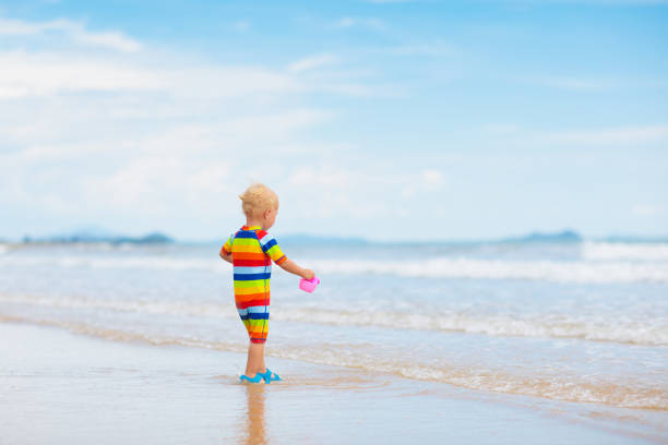 Child playing on tropical beach. Little boy digging sand at sea shore. Family summer vacation. Kids play with water and sand toys. Ocean and island fun. Travel with young children. Asia holiday.