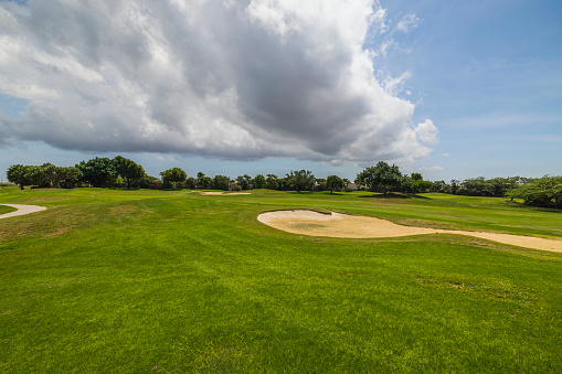 Beautiful view of green grass golf course on island of Aruba against blue sky with white clouds.