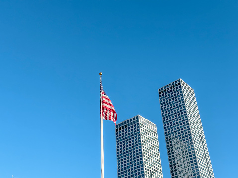 Looking up to skyscrapers and American flag