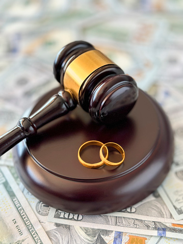 Judge gavel and wedding rings on dollar background