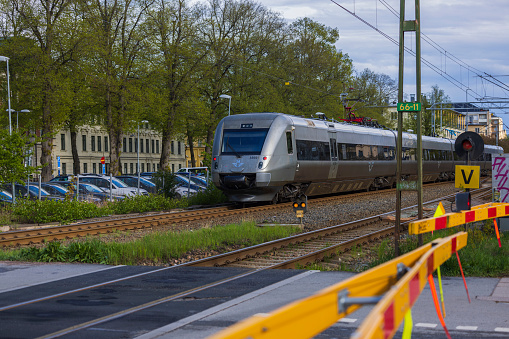 Sweden. Uppsala. 05.14.2022. Beautiful view of city center with closed automatic barrier in front of passing high-speed train.