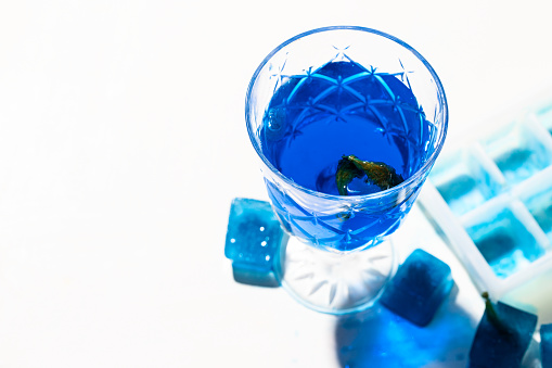 Cold blue tea with ice cubes. Butterfly pea flower  drink on white background with beautiful shadow .Copy space