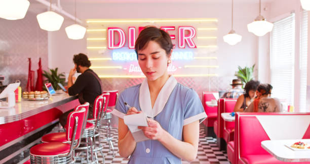 A POV shot of a waitress taking an order in a 1950s styled diner.