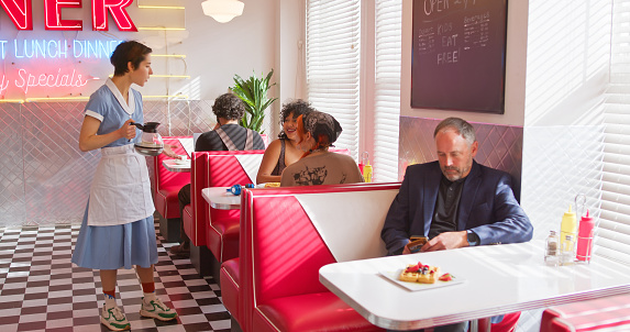 A waitress caters to the customers in a 1950s styled diner.