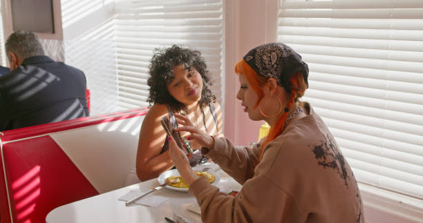 istock Still Of Two Non-Binary People Using a Smartphone In 1950s Styled Diner 1476022873