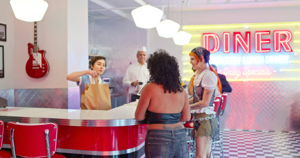istock Waitress Giving Bag To Two Non-Binary People In 1950s Styled Diner 1476023480