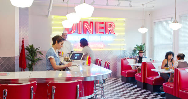 istock Waitress Writing On Her Notepad With Customers In The Background In 1950s Styled Diner 1476023485