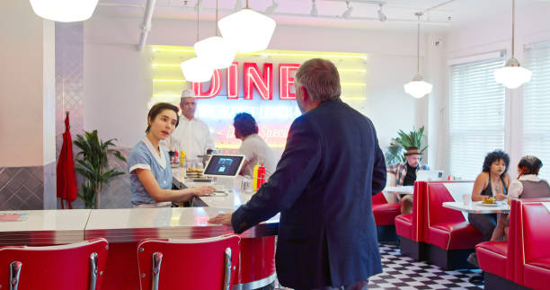istock Waitress Talking To Man In Suit In 1950s Styled Diner 1476023486
