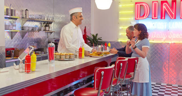 istock Man In White Button Down Shirt And Paper Cap Hands Order to Waitress 1476023494