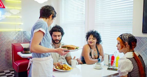 A waitress serves food to a diverse group of customers.