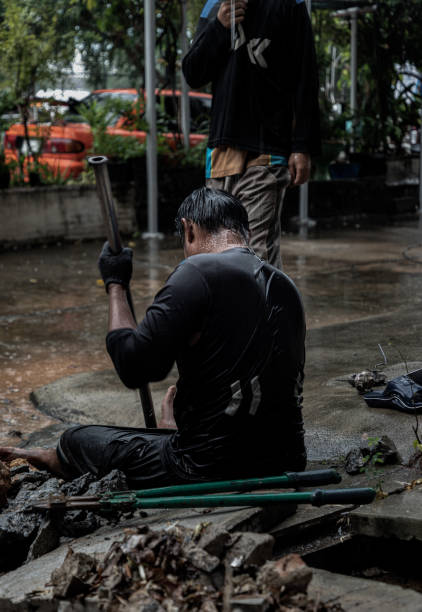 istock Utility workers using tool to fixing broken water main for commercial building water supplies during a rain. 1476024240