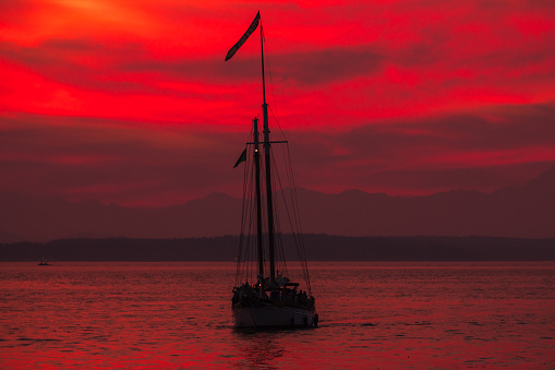 Seattle, USA - Oct 6th, 2022: A vivid sunset over Elliott bay with seattles tallest ship the Bay Lady at the Harbor Marina.