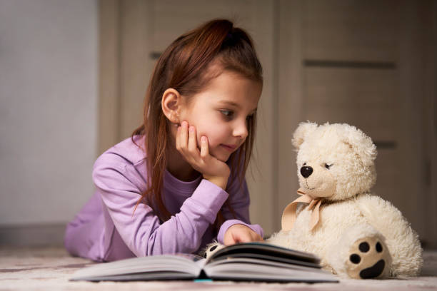 istock Cute girl lying on the floor and reading a book 1476028124