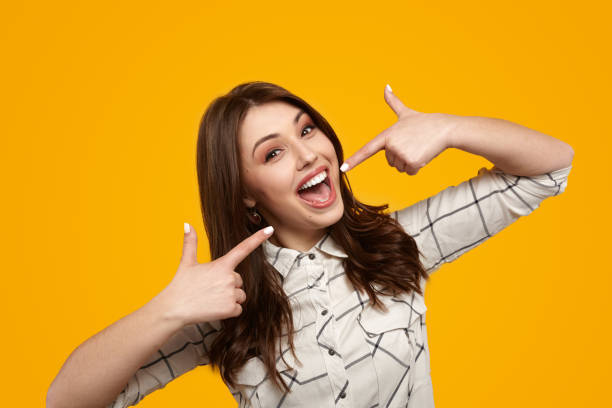 istock Delighted young lady showing smile gesture in bright yellow studio 1476041526