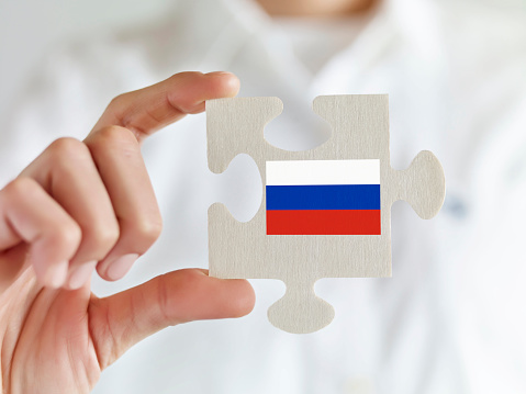 Businesswoman holding jigsaw puzzle pieces with Russian flag