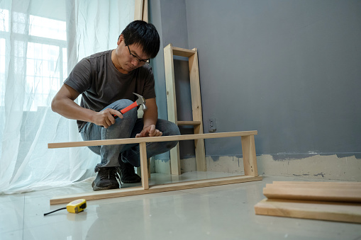 An Asian middle-aged man makes wooden furniture in DIY