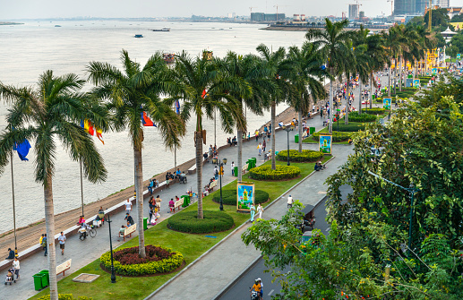 Many Cambodian citizens at sunset,busiest area in Phnom Penh at Sisowath Quay,a popular strip and pedestrian area. Tourists and Khmer families come to eat,pray and socialize,in late afternoon.