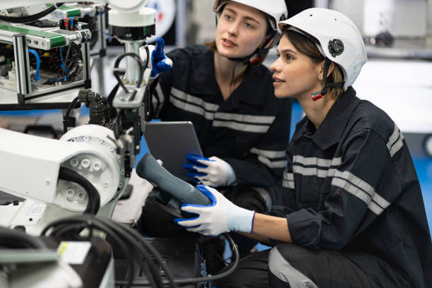 istock Two Engineer caucasian woman use remote control checking arm robot in the machine lap 1476074334