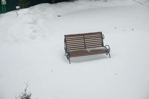 Bench in snow. Lonely shop in park in winter. Empty space. Details of park.