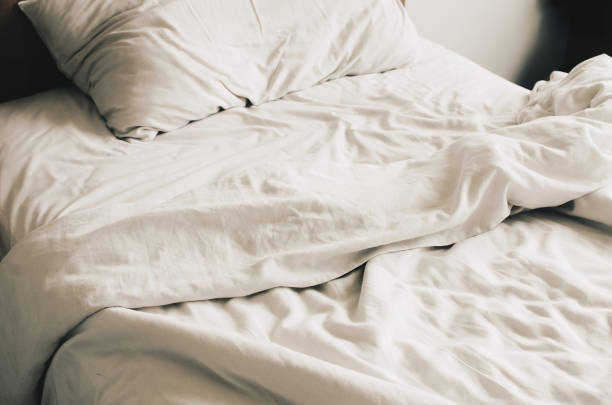 istock Messy bed with pillows close-up, white bed linen. 1476084310