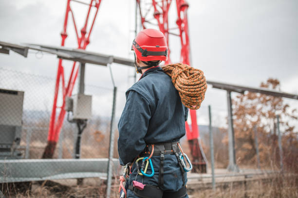 Rear view of a gas pipeline worker preparing to climb a repeater for repairs
