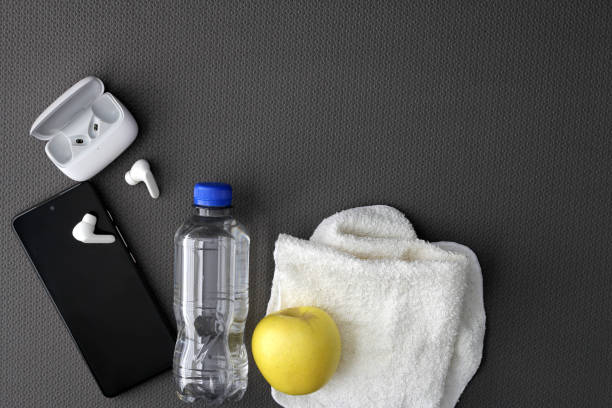istock Mat to exercise with the necessary objects such as wireless headphones, cell phone, apple, water to hydrate, sweat towel and locker keys 1476087830