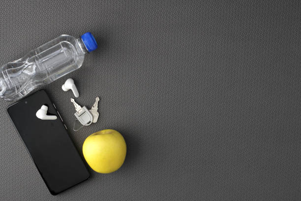 istock Mat to exercise with the necessary objects such as wireless headphones, cell phone, apple, water to hydrate, sweat towel and locker keys 1476087901