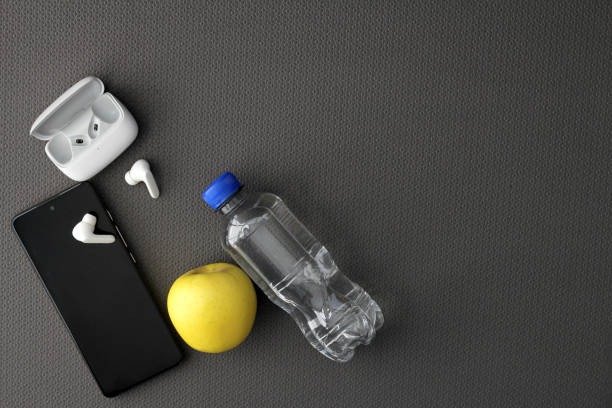 istock Mat to exercise with the necessary objects such as wireless headphones, cell phone, apple, water to hydrate, sweat towel and locker keys 1476087989