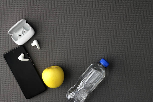 istock Mat to exercise with the necessary objects such as wireless headphones, cell phone, apple, water to hydrate, sweat towel and locker keys 1476089724