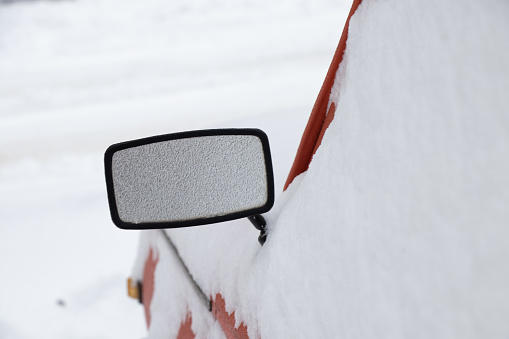 rearview mirror on an old car in the snow in winter in January