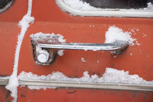 the door handle of an old car in the snow in January
