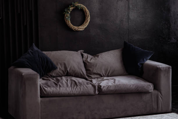 istock Gray velor sofa in a dark room against a black wall. 1476096542
