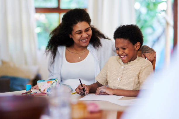 istock Laughing, creative and mother with child doing homework, studying and learning in homeschool. Happy, support and mom helping son with education, drawing or alphabet lesson at a home desk together 1476098511