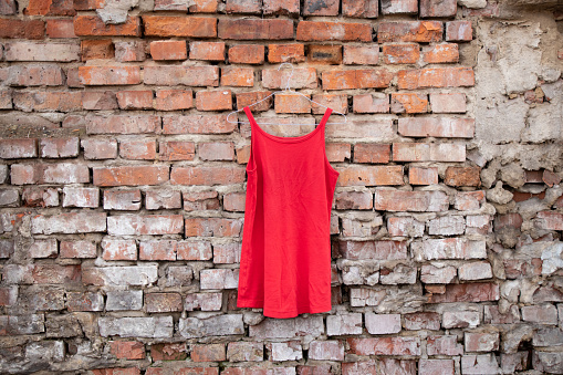vestido rojo de mujer colgado en una vieja pared de ladrillo afuera photo