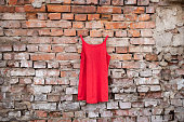 red womens dress hanging on a brick old wall outside