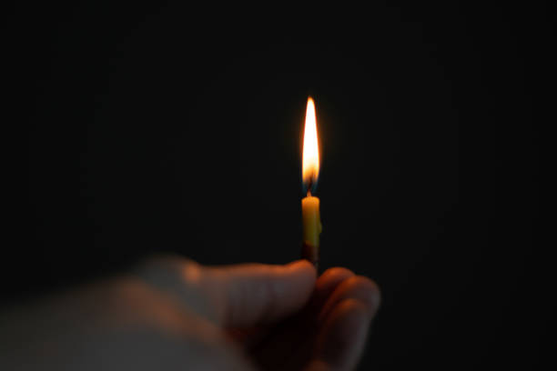 istock female hand holding a burning candle in the dark 1476101353