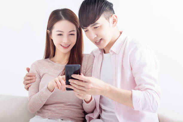 istock Young  couple using smart phone , browsing internet, chatting online, relaxing on sofa at home 1476102588