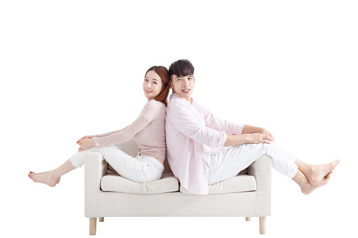 Happy Young couple sitting on sofa against white background