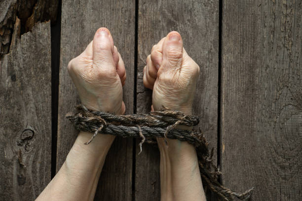 tied hands with rope of old woman on wooden background tied hands with rope of old woman on wooden table Trafficking stock pictures, royalty-free photos & images