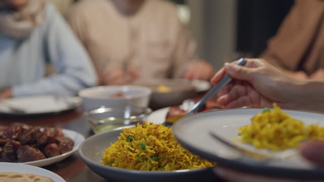 Close-up dish of halal food biryani rice on plate. Asia muslim sweet daughter serve food to mother Ramadan dinner together at home. Family celebration end of Eid al-Fitr togetherness.