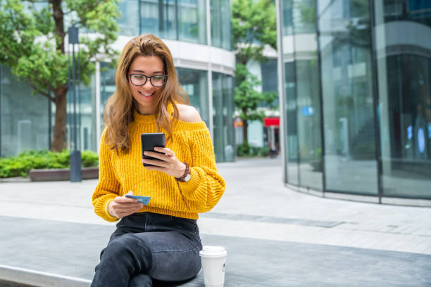 Woman holding credit card and using smartphone while making payment online