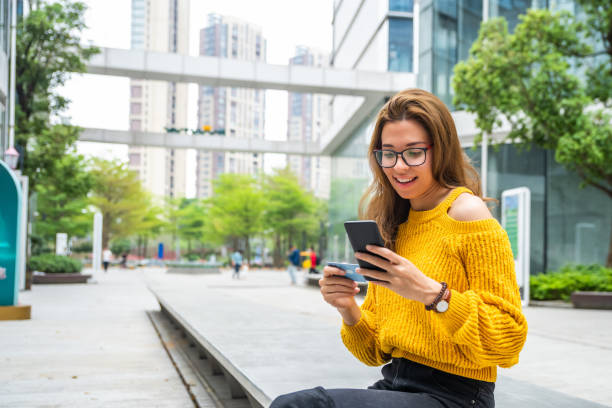 istock Young female sitting outdoors doing mobile payment online 1476118632