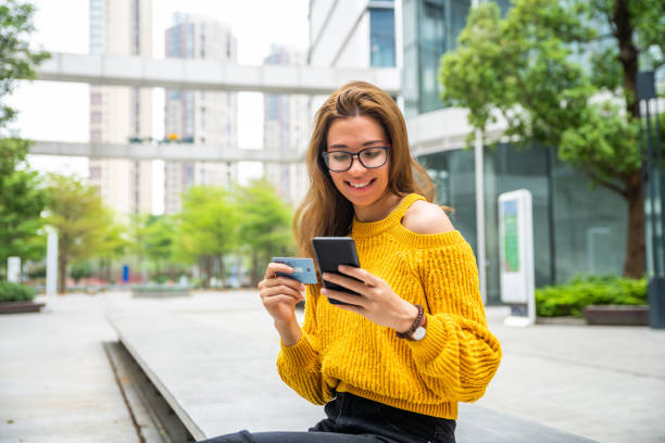 istock Young woman holding her credit card while using her cellphone 1476118634