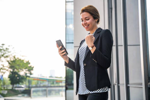 istock Positive young female entrepreneur using phone on street 1476119689